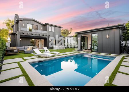 Ein atemberaubendes modernes Haus in einer sonnigen kalifornischen Stadt verfügt über einen großen Swimmingpool, der von einer üppigen Landschaft umgeben ist Stockfoto