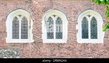 Drei bogenförmige Fenster auf einer roten Backsteinmauer am Queens' College, University of Cambridge, England. Stockfoto