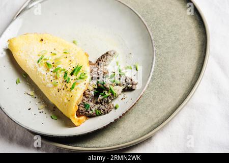 Omelette mit Morchelpilzen in einer cremigen Sauce mit Kräutern. Stockfoto