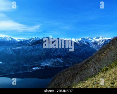 Malerischer Blick auf die Berge, die im Winter über dem Bohinjer See aufragen, schneebedeckt inkl. Mahavcek, Tolminski Kuk und Vogel aus Vogar in Triglav Stockfoto