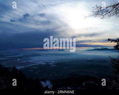 Malerischer Blick auf die schneebedeckte Region Sorsko Polje und Gorenjska in Slowenien mit dem Hügel Smarna Gora im Hintergrund Stockfoto