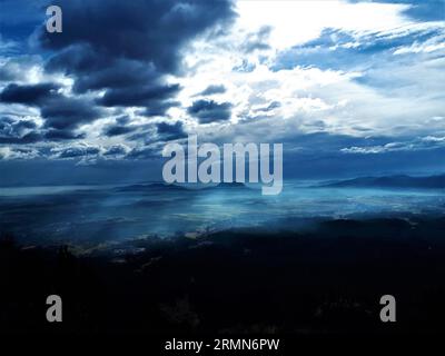 Malerischer Blick auf Sorsko polje in der slowenischen Region Gorenjska, bedeckt mit Nebel und Sonne, die auf dem Nebel durch die Wolken scheint Stockfoto