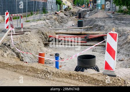 Blick auf den Straßenumbau mit tiefem Graben, alten und ersetzten unterirdischen Rohren, neuer vertikaler Kunststoffbrunnen Stockfoto