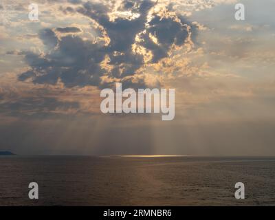 Sonnenstrahl durch den Dunst. Dramatischer Himmel mit leuchtenden Wolken und Meer bei Sonnenuntergang Stockfoto