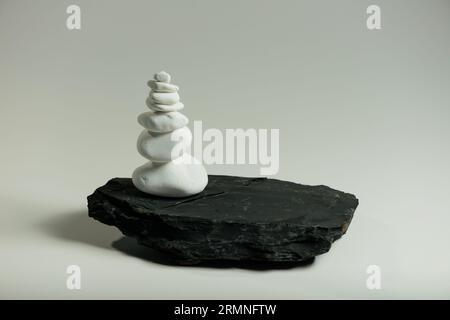 Weiße, glatte Steine, die auf einem schwarzen, flachen Stein balanciert sind Stockfoto