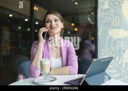 Junge, glückliche Geschäftsfrau, die auf einen Mann wartet, der zum Mittagessen in einem Café auf ein Date wartet Stockfoto