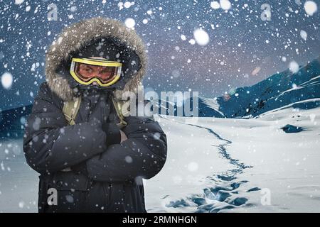 Ein männlicher Tourist verirrte sich, verirrte sich und fror beim Wandern im Winter in den Bergen, fiel nachts unter den Schneefall Stockfoto