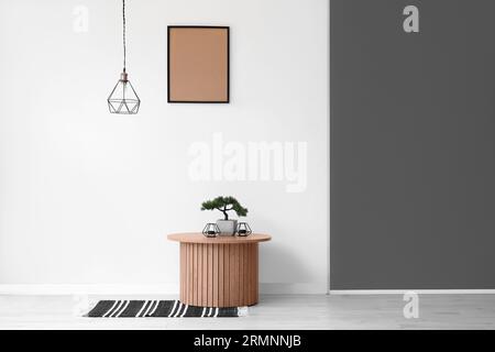 Couchtisch aus Holz mit Bonsaibaum und Kerzenständer in der Nähe der weißen Wand Stockfoto