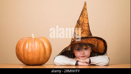 Alles Gute Zu Halloween. Lächelnder Junge mit Hexenhut und halloween-Kürbis. Halloween-Kind mit magischem Hut. Kleines Kind im Zauberkostüm mit Jack-o-Laterne Stockfoto