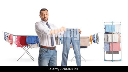 Mann, der eine Jeans vor Gestellen hält, um Kleidung isoliert auf weißem Hintergrund zu trocknen Stockfoto