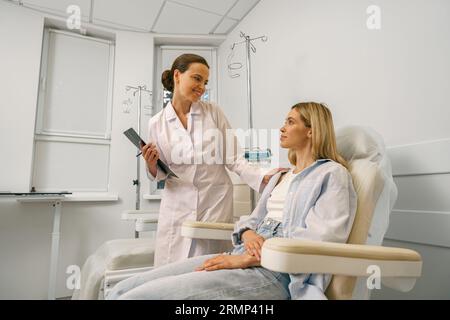 Krankenschwester oder Arzt, der mit dem Patienten spricht, während er ihn auf den Infusionstropfen im Krankenhaus vorbereitet Stockfoto