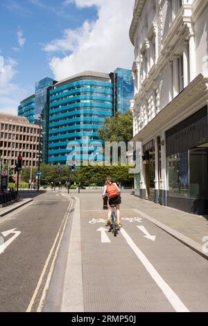 Ein Radfahrer auf einer Radspur in der Nähe des postmodernen St Botolph Building in Houndsditch, entworfen von Grimshaw Architects, London, EC3, England, Großbritannien Stockfoto