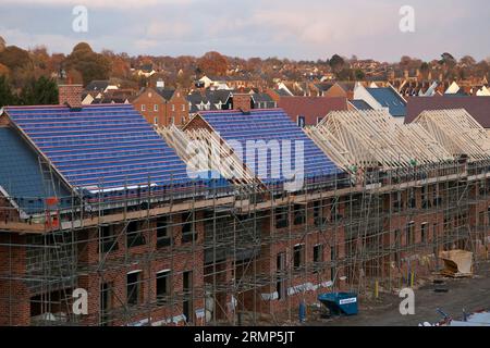 Neues Wohneigentum in verschiedenen Stadien der Fertigstellung: Eine Reihe von Häusern, teilweise gefertigte Dächer mit Sparren, Pfetten, Latten und Membranen. Stockfoto