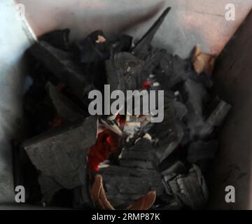 Holzkohlestücke auf einem Grillherd, die ein Feuer zum Kochen oder Braten von Fleisch anzünden Stockfoto