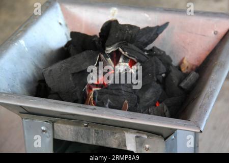 Holzkohlestücke auf einem Grillherd, die ein Feuer zum Kochen oder Braten von Fleisch anzünden Stockfoto