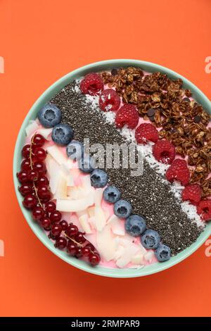 Leckere Smoothie-Schüssel mit frischen Beeren und Müsli auf orangefarbenem Hintergrund, Draufsicht Stockfoto