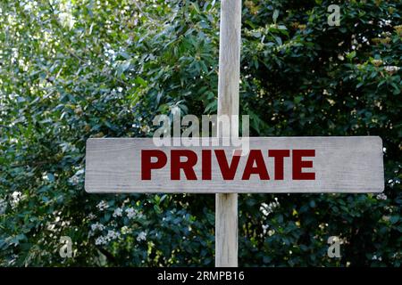 Hölzernes Schild mit dem Wort Privat in der Nähe grüner Büsche Stockfoto