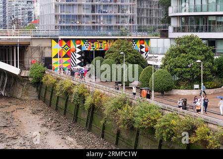 Menschen, die an einem regnerischen Tag in London durch den Eingang des Grosvenor Arch unter der Grosvenor Railway Bridge zum Battersea Power Station gehen. England Stockfoto