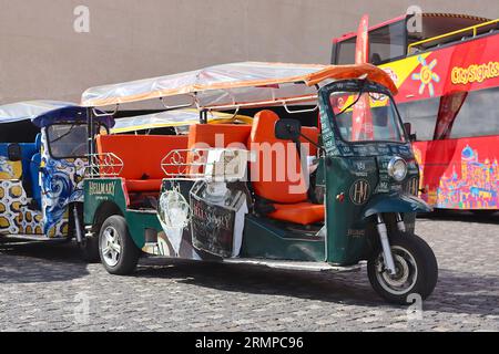 Hoch dekorierte elektrische Tuck-Tuck-Auto-Rickshaws, die geparkt sind und auf Kunden warten, die vom Kreuzfahrthafen in Lissabon, Portugal, im April 2023 auftauchen Stockfoto