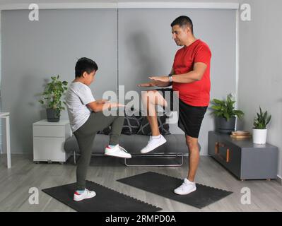 Latino Vater und Sohn haben gemeinsam in ihrem Wohnzimmer trainiert, um Gewicht zu verlieren und ihre Gesundheit zu verbessern Stockfoto