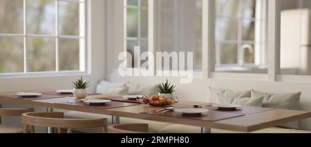 Ein Esstisch mit einem schönen Esstisch, Holzstühlen und einer weißen Couch in einem modernen Esszimmer. Restaurant, Essbereich, Esszimmer. Stockfoto