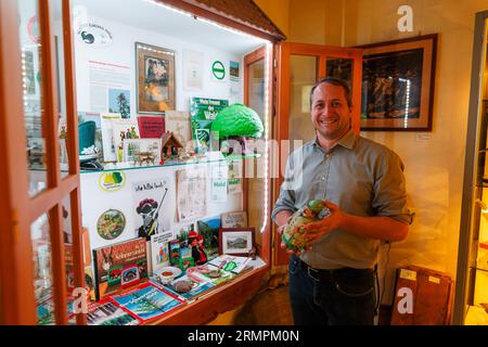 PRODUKTION - 28. August 2023, Baden-Württemberg, Münstertal: Markus Herbener, Direktor des „Museum Münstertal – Museum für Bergbau, Forsten, Siedlung und Lokalgeschichte des Münstertals“ steht im Museum mit einem Bierbecher in Form eines Forstarbeiters. Die Gemeinde Münstertal liegt im südlichen Schwarzwald und hat etwa 5100 Einwohner. Das öffentliche Bild des Schwarzwaldes ist geprägt von Kuckucksuhren, der Schwarzwaldklinik und dem Pollenhut - wie viel davon ist heute noch wahr? (Zu dpa 'Summer Series: Clichés in Baden-Württemberg - Bollenhut and Co - Schwarz Für Stockfoto