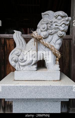 Japan, Kyushu. Löwenhund-Wächter im buddhistischen Tempel Tennen-JI und Shinto-Schrein. Das Shimenawa-Seil weist auf einen heiligen oder rituell reinen Raum hin. Der Klo Stockfoto