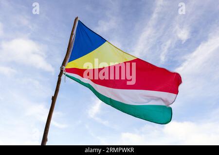 Die Flagge der Seychellen winkt an einem sonnigen Tag im Wind unter bewölktem blauem Himmel, Nahaufnahme Foto Stockfoto