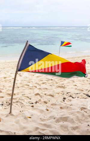 Die Flaggen der Seychellen wehten am Strand und wehten tagsüber im Wind Stockfoto