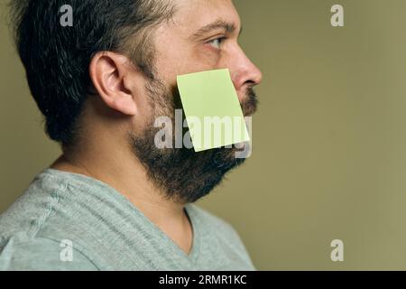 Gesichtsporträt eines Mannes mit einem Profilbart und mit leeren Papieraufklebern bedeckt Stockfoto