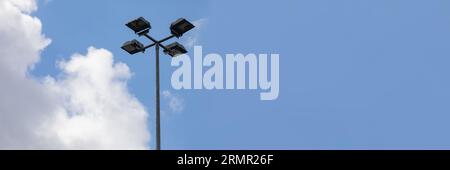 Im Panoramablick eine Straßenlaterne vor einem mit weißen Wolken bedeckten Himmel. Stockfoto