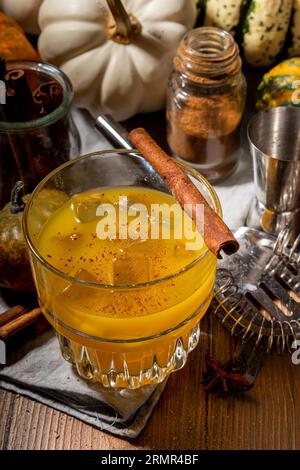 Hausgemachter alkoholischer Kürbis-Zimt-Cocktail, erfrischender eisgekühlter Kürbis-Gewürz-altmodischer Cocktail, Holzküchentisch im Hintergrund Kopierraum Stockfoto