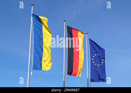 Die Flaggen Der Ukraine, Deutschlands Und Der Europäischen Union Fliegen Seite An Seite Gegen Den Blauen Himmel Stockfoto