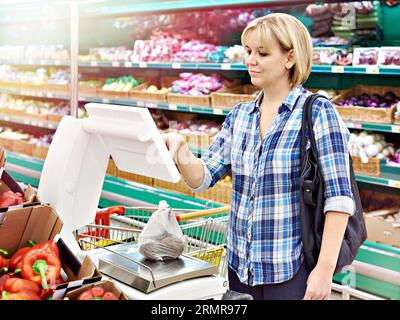 Frau, die Gemüse im Laden wiegt Stockfoto