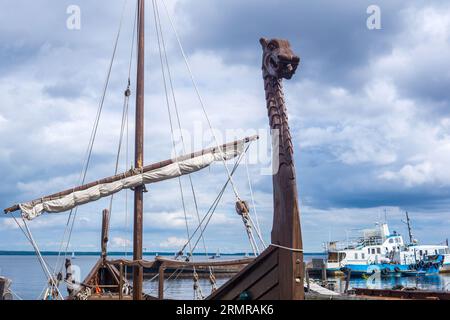 Aushängeschild auf dem Bug einer großformatigen Nachbildung eines wikingerschiffes, das im Hafen vor Anker liegt Stockfoto