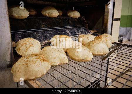 Traditionelles ägyptisches Fladenbrot aish Baladi. Frisch gebackenes Fladenbrot aus dem Ofen. Traditioneller ägyptischer Straßenbäcker. Stockfoto