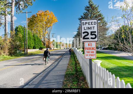 Traditionelles amerikanisches Geschwindigkeitslimit und keine Parkschilder über einem weißen Zaun an der Ocean Ave, Kennebunkport, Maine, USA, gesäumt von goldenen Fallbäumen. Stockfoto