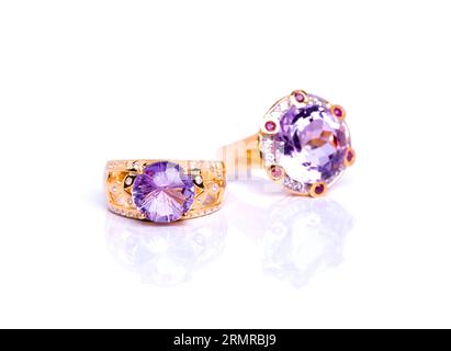 Nahaufnahme von zwei exquisiten Ringen mit glänzenden Amethyst-Steinen, die elegant auf einem reinweißen Hintergrund platziert sind und Luxus und Romantik ausstrahlen Stockfoto