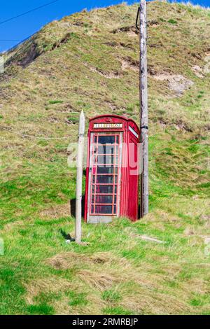 Die ikonische, traditionelle britische Red Telephone Box, die sich auf einem Hügel im kleinen Fischerdorf Crovie in Aberdeenshire, Schottland, befindet Stockfoto