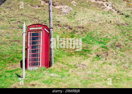 Die ikonische, traditionelle britische Red Telephone Box, die sich auf einem Hügel im kleinen Fischerdorf Crovie in Aberdeenshire, Schottland, befindet Stockfoto