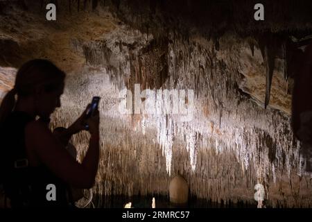 Manacor, Spanien. 28. August 2023. Besucher der Drachenhöhlen in Porto Cristo, einem der meistbesuchten Orte auf Mallorca. Mit einer maximalen Höhe von 25 Metern unter der Oberfläche ist der Weg etwa 1,2 Kilometer lang und hat eine große Anzahl von Stalaktiten und Stalagmiten. Die Höhlen verstecken sich in einem großen unterirdischen See, dem Lake Martel, der als einer der größten unterirdischen Seen der Welt gilt. Quelle: Clara Margais/dpa/Alamy Live News Stockfoto