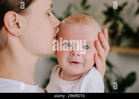 Nahaufnahme eines Porträts der liebevollen jungen kaukasischen Mutter, die die süße, glückliche Wange des Kleinkindes küsst, der Familie, die einen zarten Moment genießt, der liebevollen, wunderschönen Mutter mit einem Klecks Stockfoto