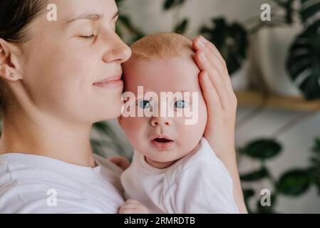 Liebevolle Mom umarmt streichelnde kleine Kleinkinder. Nahaufnahme eines liebevollen jungen Mutter, die in den Armen hält, umarmt, kleines Baby, Kind, das in l steht Stockfoto