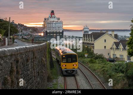 Cobh, Cork, Irland. 30. August 2023. Die Cunard-Linienschiff Queen Victoria liegt an ihrem Liegeplatz, als das Kreuzfahrtschiff Silver Dawn im Hafen ankommt, während ein Zug am frühen Morgen in Cobh, Co. Ankommt Cork, Irland. David Creedon / Alamy Live News Stockfoto