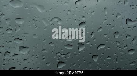 Viele Regentropfen auf durchsichtigem Glas, Wassertropfen draußen in der Regenzeit Stockfoto