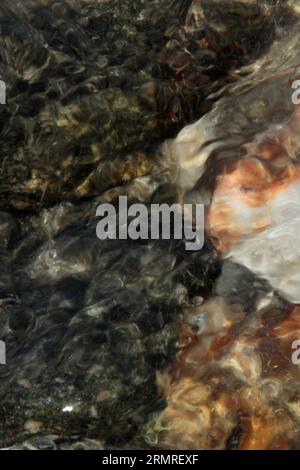 Weiße, graue und rötlich braune Felsen unter Wasser Stockfoto