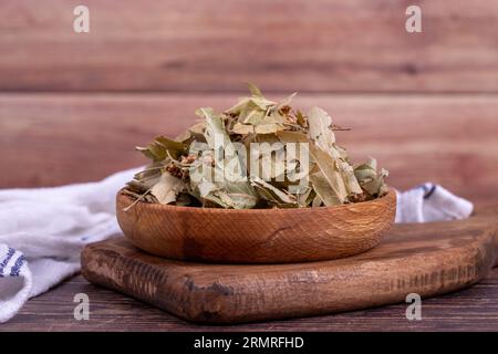 Getrocknete Lindenblüten. Frische Blumen und Lindenblätter in Holzschale. Kräutermedizin Stockfoto