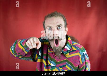 Wütender Hipster-Mann, der auf die Kamera zeigte, staunte und mit überraschtem Ausdruck Stockfoto