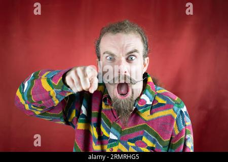 Wütender Hipster-Mann, der auf Kameraschreien und mit wütendem Ausdruck zeigt Stockfoto