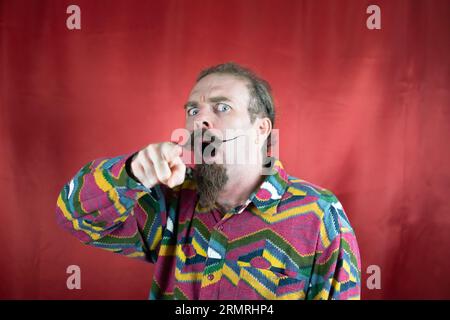 Wütender Hipster-Mann, der auf die Kamera zeigte, staunte und mit überraschtem Ausdruck Stockfoto